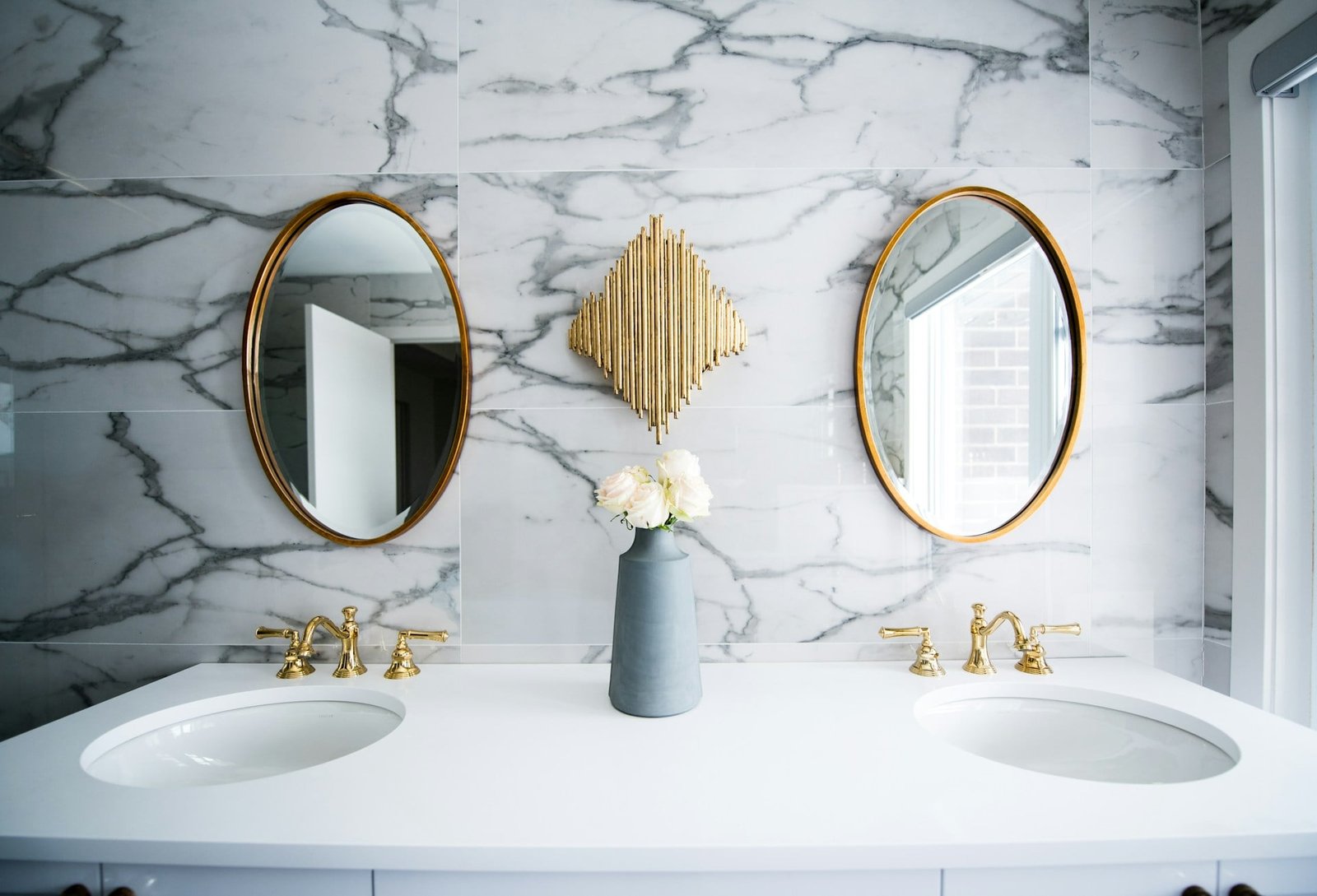 bathroom with marble wall, two sinks, and two mirrors